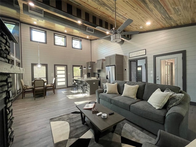 living room featuring wood ceiling, ceiling fan, high vaulted ceiling, a fireplace, and hardwood / wood-style floors