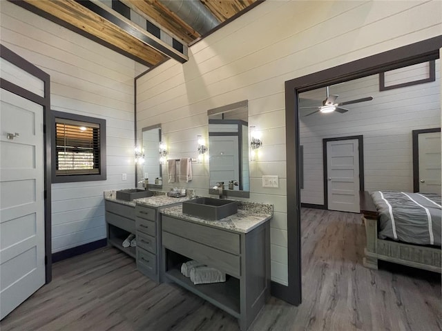 bathroom featuring beamed ceiling, high vaulted ceiling, wood-type flooring, wooden walls, and vanity