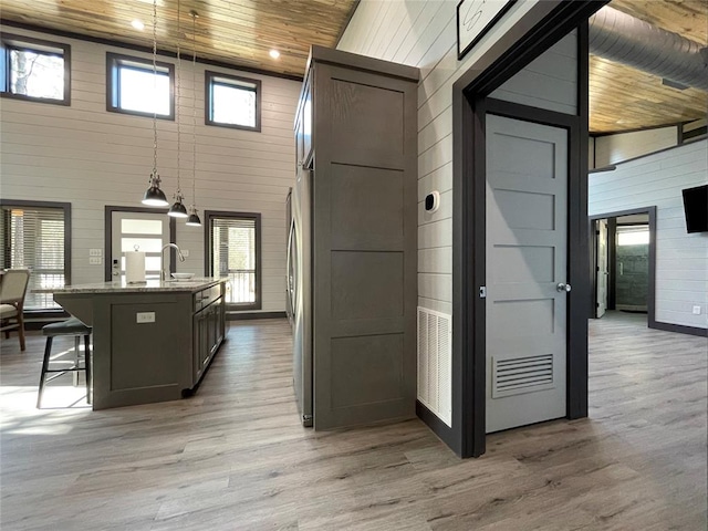 corridor with sink, wood ceiling, a high ceiling, and light wood-type flooring