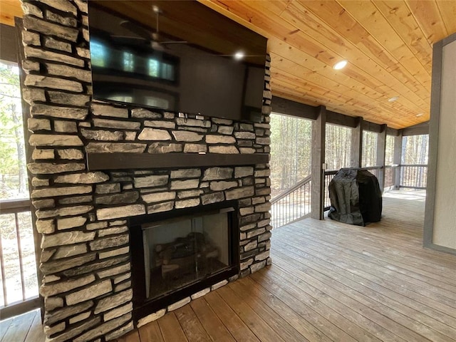 room details with ceiling fan, a stone fireplace, wood-type flooring, and wooden ceiling