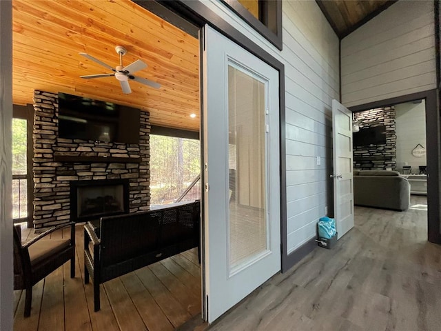 interior space featuring vaulted ceiling, hardwood / wood-style floors, wooden ceiling, and an outdoor stone fireplace