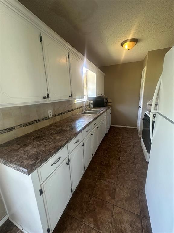 kitchen with white cabinetry, sink, tasteful backsplash, white refrigerator, and a textured ceiling