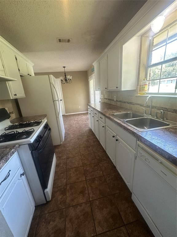 kitchen featuring plenty of natural light, white cabinetry, sink, and white appliances