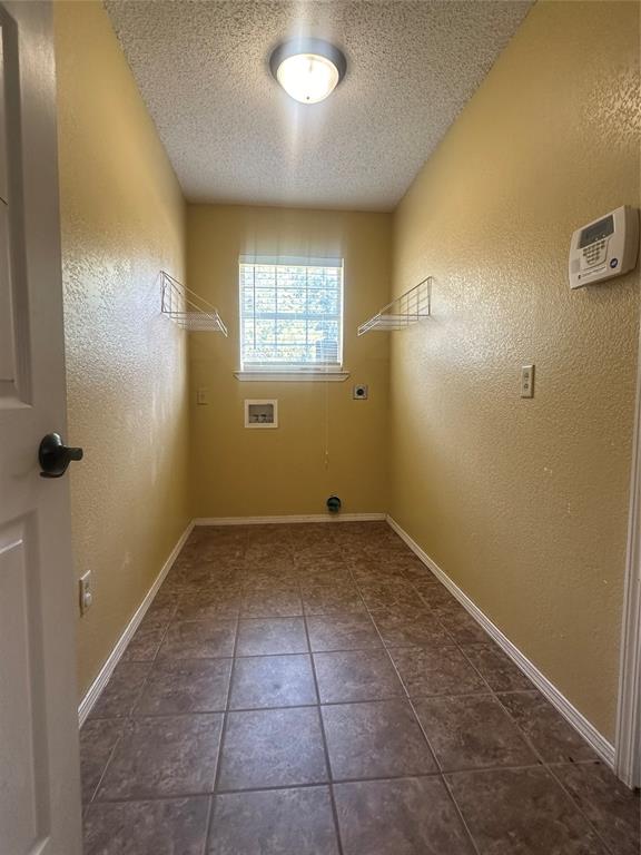 laundry area featuring washer hookup, a textured ceiling, dark tile patterned flooring, and electric dryer hookup