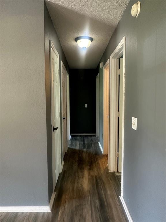 hall featuring a textured ceiling and dark hardwood / wood-style flooring