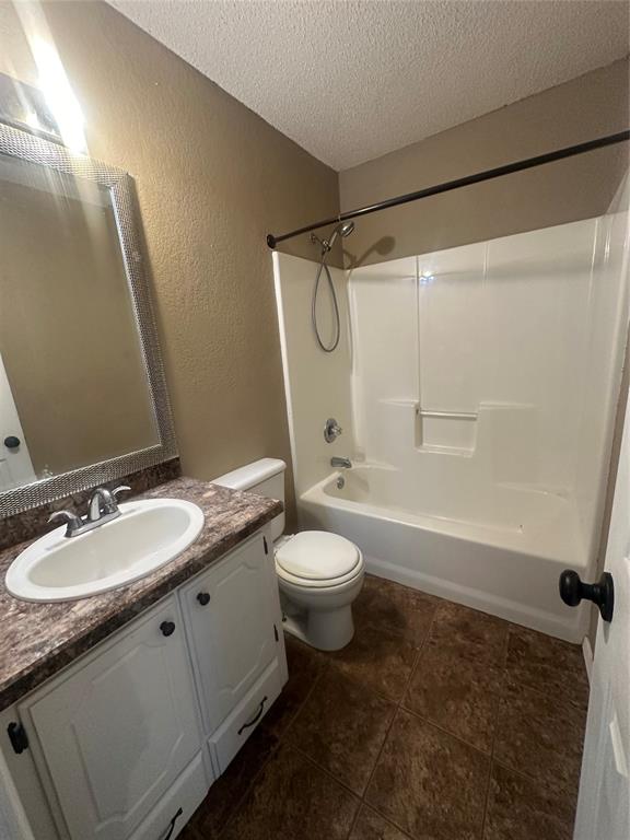 full bathroom with vanity, shower / tub combination, tile patterned floors, toilet, and a textured ceiling