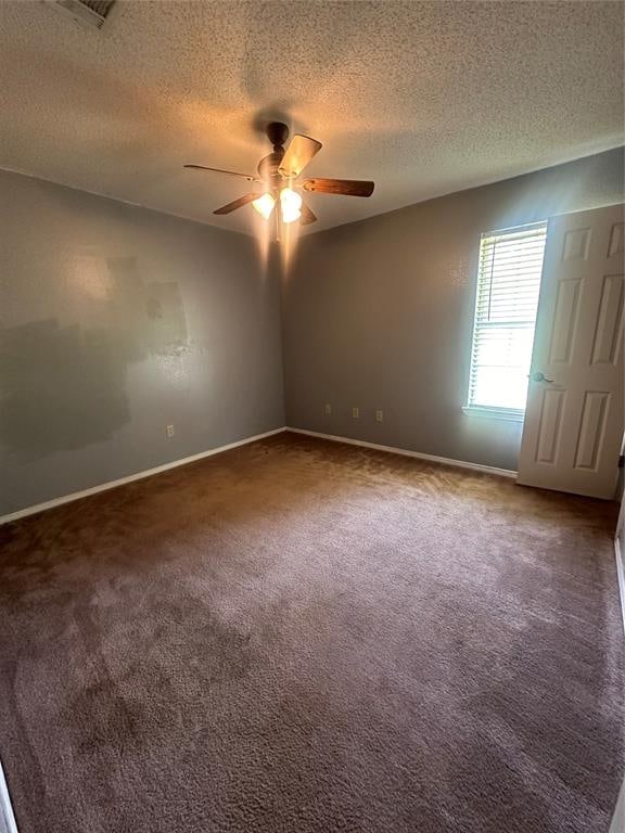 spare room with a textured ceiling and dark colored carpet