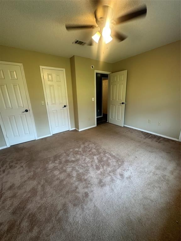 unfurnished bedroom with ceiling fan, carpet floors, and a textured ceiling