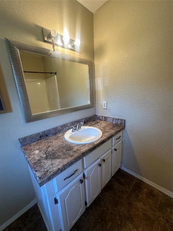 bathroom with tile patterned floors, a shower, and vanity