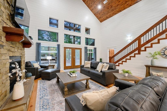 living room featuring wood ceiling, light hardwood / wood-style flooring, high vaulted ceiling, and a fireplace