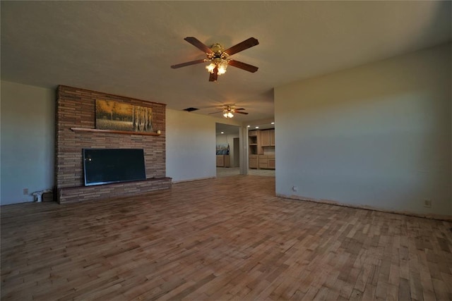 unfurnished living room featuring a fireplace, hardwood / wood-style floors, and ceiling fan