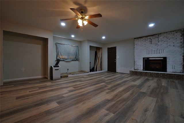 unfurnished living room featuring ceiling fan, a fireplace, and dark hardwood / wood-style floors