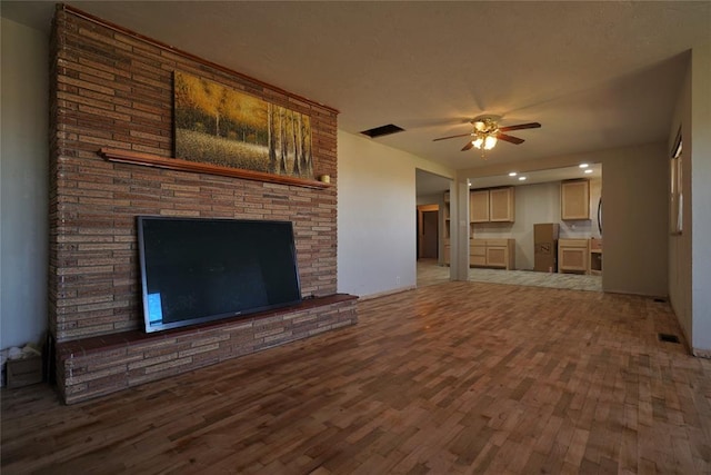 unfurnished living room featuring ceiling fan, a fireplace, and wood-type flooring