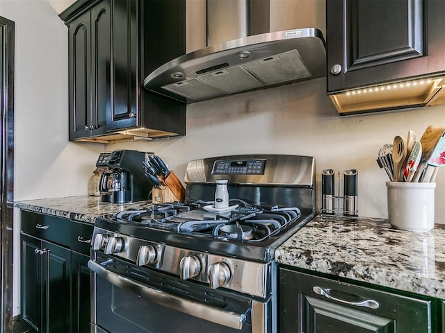 kitchen with light stone countertops, stainless steel gas range oven, and range hood