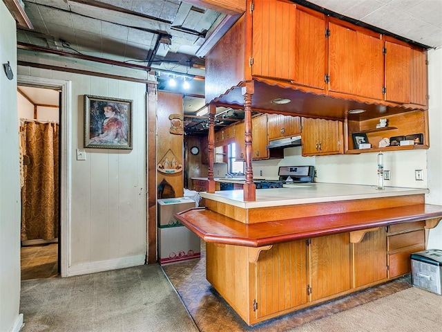 kitchen with carpet flooring, kitchen peninsula, wood walls, and black range