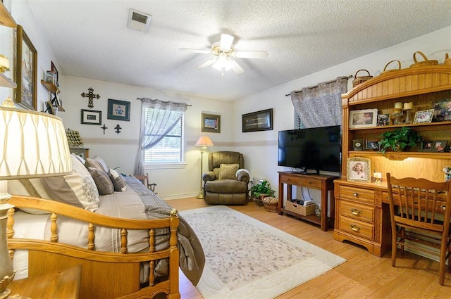 living room featuring ceiling fan, a textured ceiling, and light hardwood / wood-style flooring