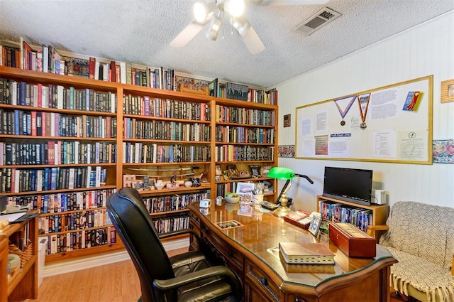 home office featuring a textured ceiling, light hardwood / wood-style floors, ceiling fan, and wood walls