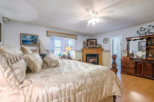 bedroom with ceiling fan, light hardwood / wood-style floors, and a textured ceiling