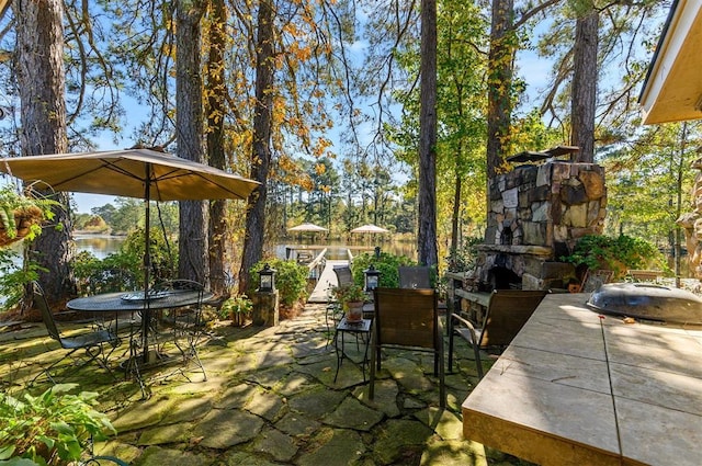 view of patio with an outdoor stone fireplace and a water view