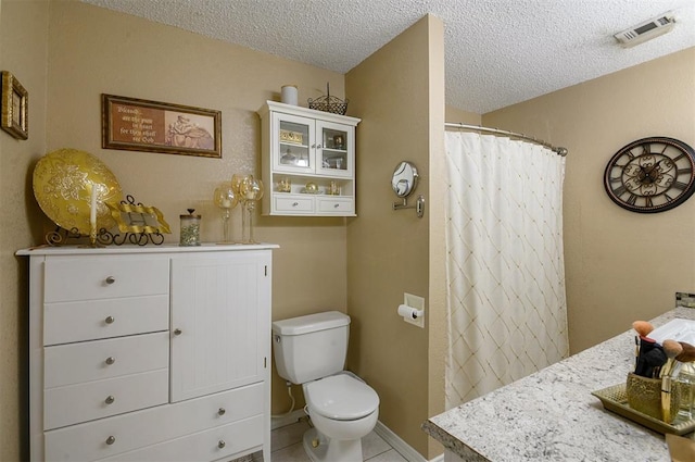 bathroom with vanity, tile patterned flooring, toilet, a textured ceiling, and walk in shower