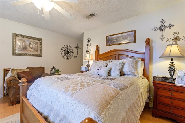 bedroom featuring ceiling fan, light hardwood / wood-style flooring, and a textured ceiling