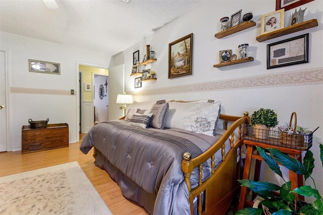 bedroom with a textured ceiling, light hardwood / wood-style floors, and ceiling fan