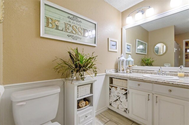 bathroom with a textured ceiling, vanity, toilet, and tile patterned floors