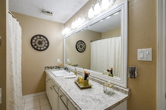 bathroom featuring tile patterned flooring, vanity, and a textured ceiling