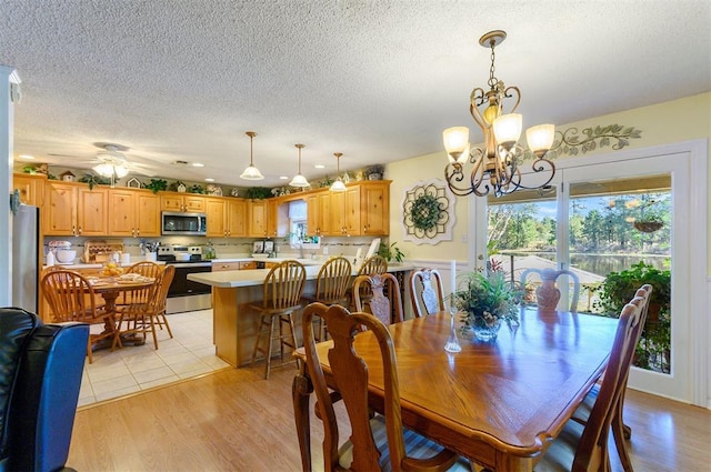 dining space featuring a textured ceiling, ceiling fan with notable chandelier, and light hardwood / wood-style flooring