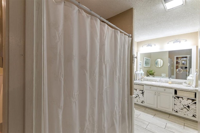 bathroom with hardwood / wood-style floors, vanity, and a textured ceiling