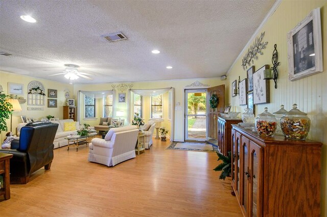 living room with ceiling fan, crown molding, light hardwood / wood-style floors, and a textured ceiling