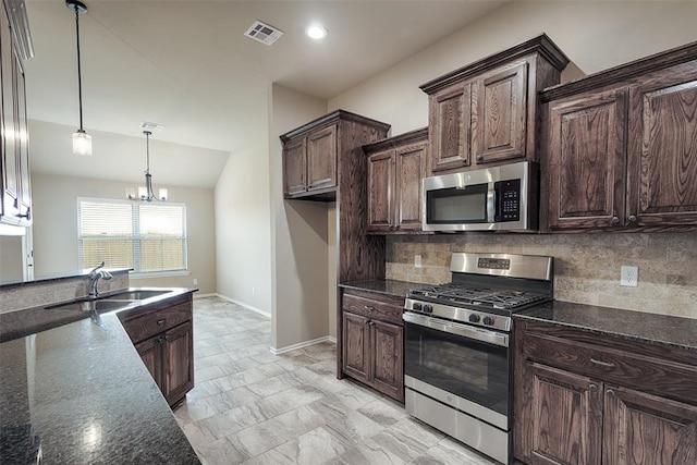 kitchen with decorative backsplash, appliances with stainless steel finishes, dark brown cabinets, a chandelier, and hanging light fixtures