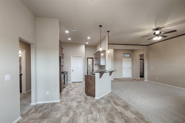 kitchen with a kitchen bar, pendant lighting, light colored carpet, and ceiling fan