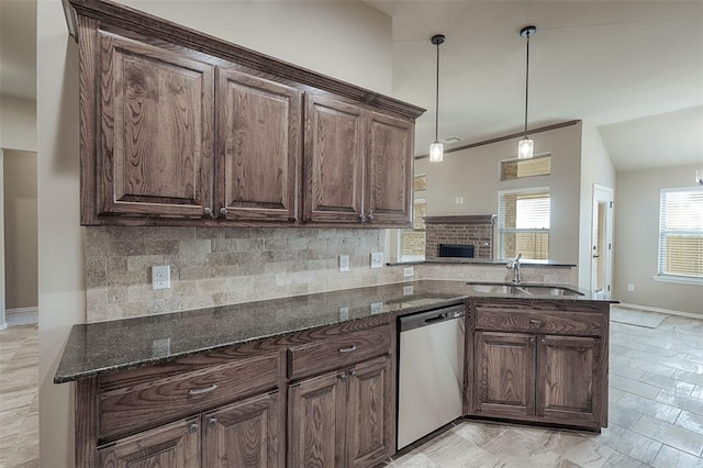 kitchen with sink, stainless steel dishwasher, kitchen peninsula, dark stone countertops, and decorative light fixtures