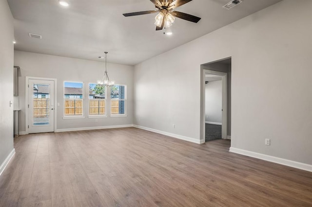 unfurnished room with ceiling fan with notable chandelier and hardwood / wood-style flooring