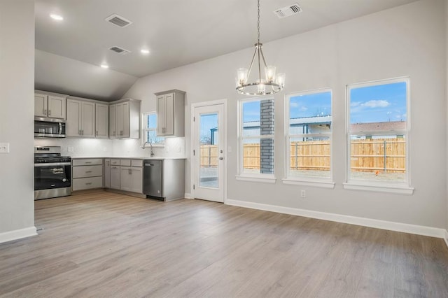 kitchen featuring lofted ceiling, stainless steel appliances, light hardwood / wood-style flooring, and a healthy amount of sunlight