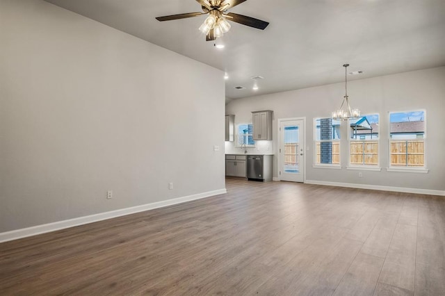 unfurnished living room featuring ceiling fan with notable chandelier and dark wood-type flooring