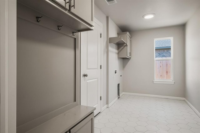 washroom with hookup for an electric dryer, light tile patterned floors, and cabinets