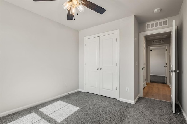 unfurnished bedroom featuring ceiling fan, a closet, and dark colored carpet