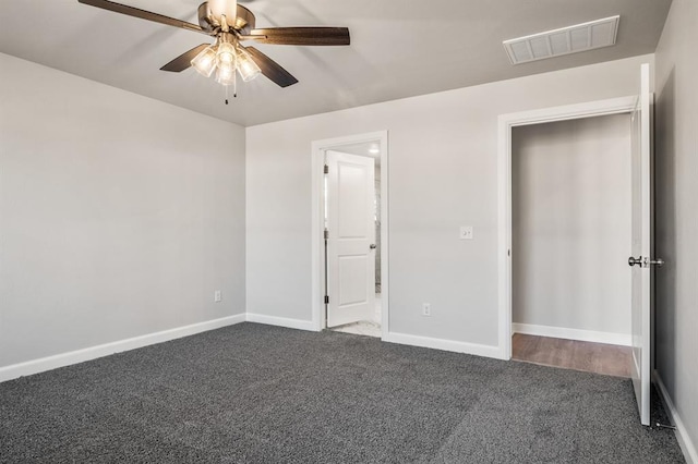 unfurnished bedroom with ceiling fan and dark colored carpet