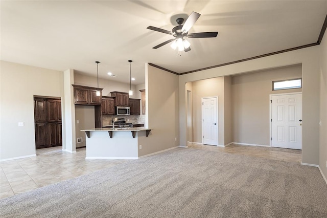 kitchen with a kitchen bar, stainless steel appliances, light colored carpet, crown molding, and hanging light fixtures