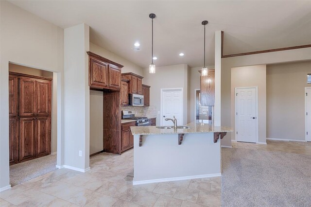 kitchen with sink, light stone counters, a kitchen bar, light carpet, and appliances with stainless steel finishes