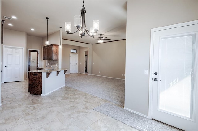 kitchen featuring light carpet, ceiling fan with notable chandelier, sink, decorative light fixtures, and a kitchen bar