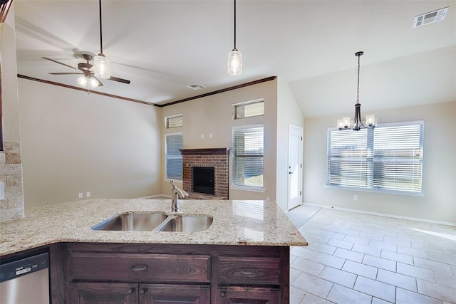 kitchen featuring sink, a brick fireplace, stainless steel dishwasher, lofted ceiling, and ceiling fan with notable chandelier