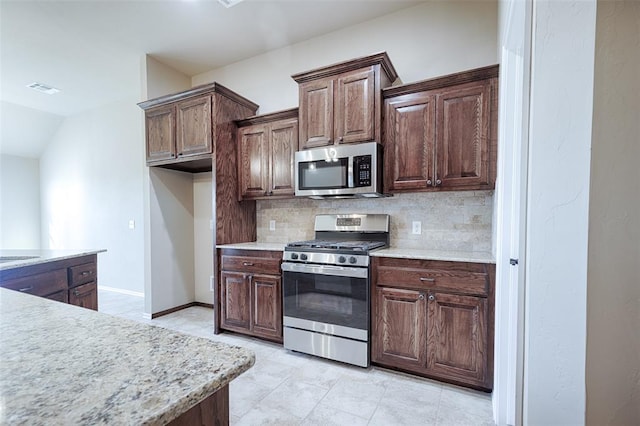 kitchen with dark brown cabinetry, decorative backsplash, and stainless steel appliances