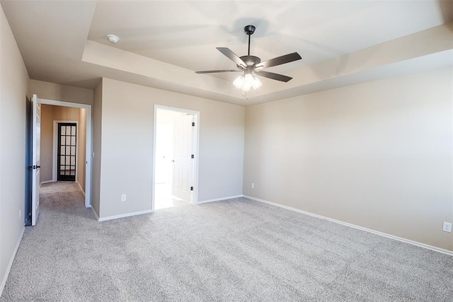 unfurnished bedroom featuring light colored carpet, a raised ceiling, and ceiling fan