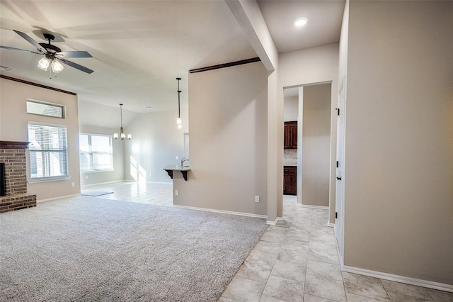 unfurnished living room with light carpet, ceiling fan with notable chandelier, and a fireplace