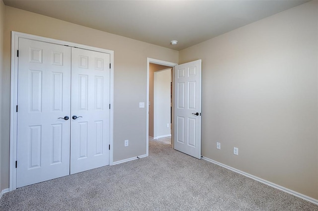 unfurnished bedroom featuring light carpet and a closet