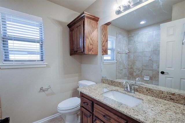 bathroom with tiled shower, vanity, and toilet