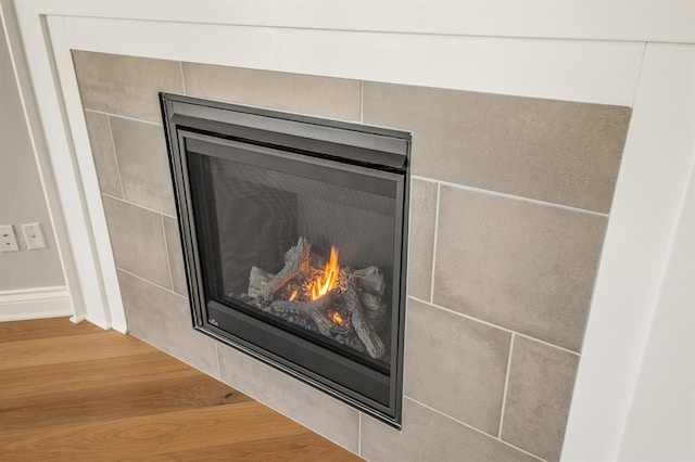 interior details featuring a tile fireplace and hardwood / wood-style flooring